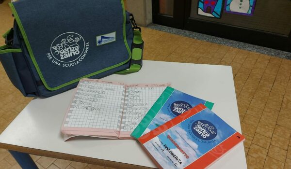 borsa senza zaino, quaderno aperto con parole scritte, due quaderni chiusi